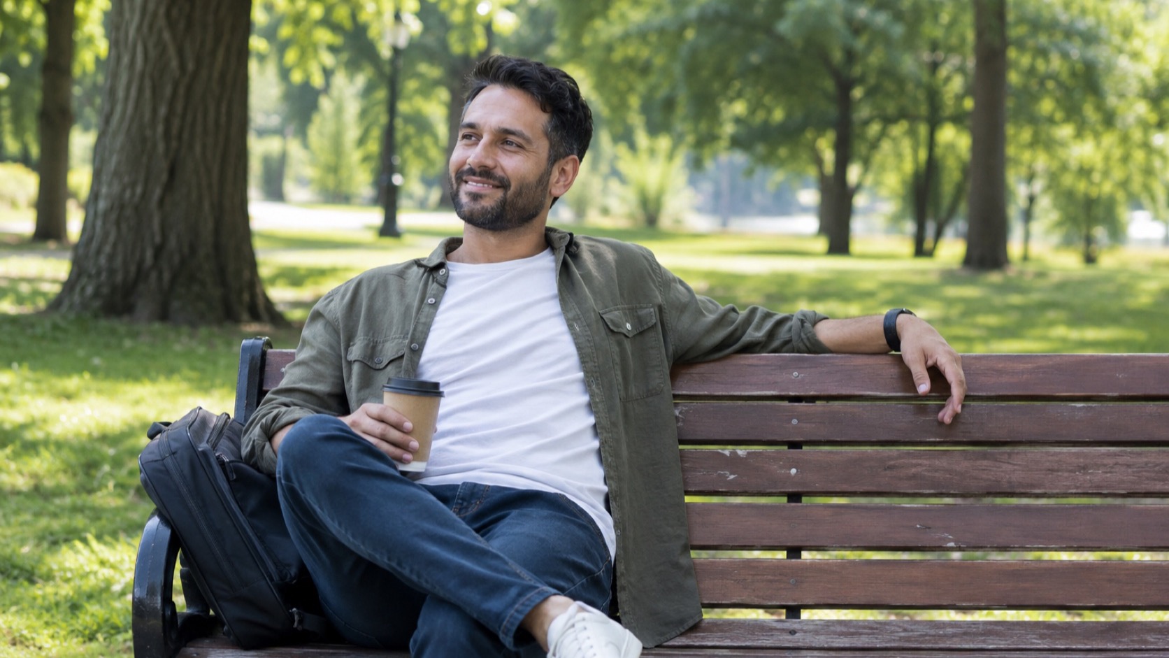 Adult relaxes on a park bench in daylight.