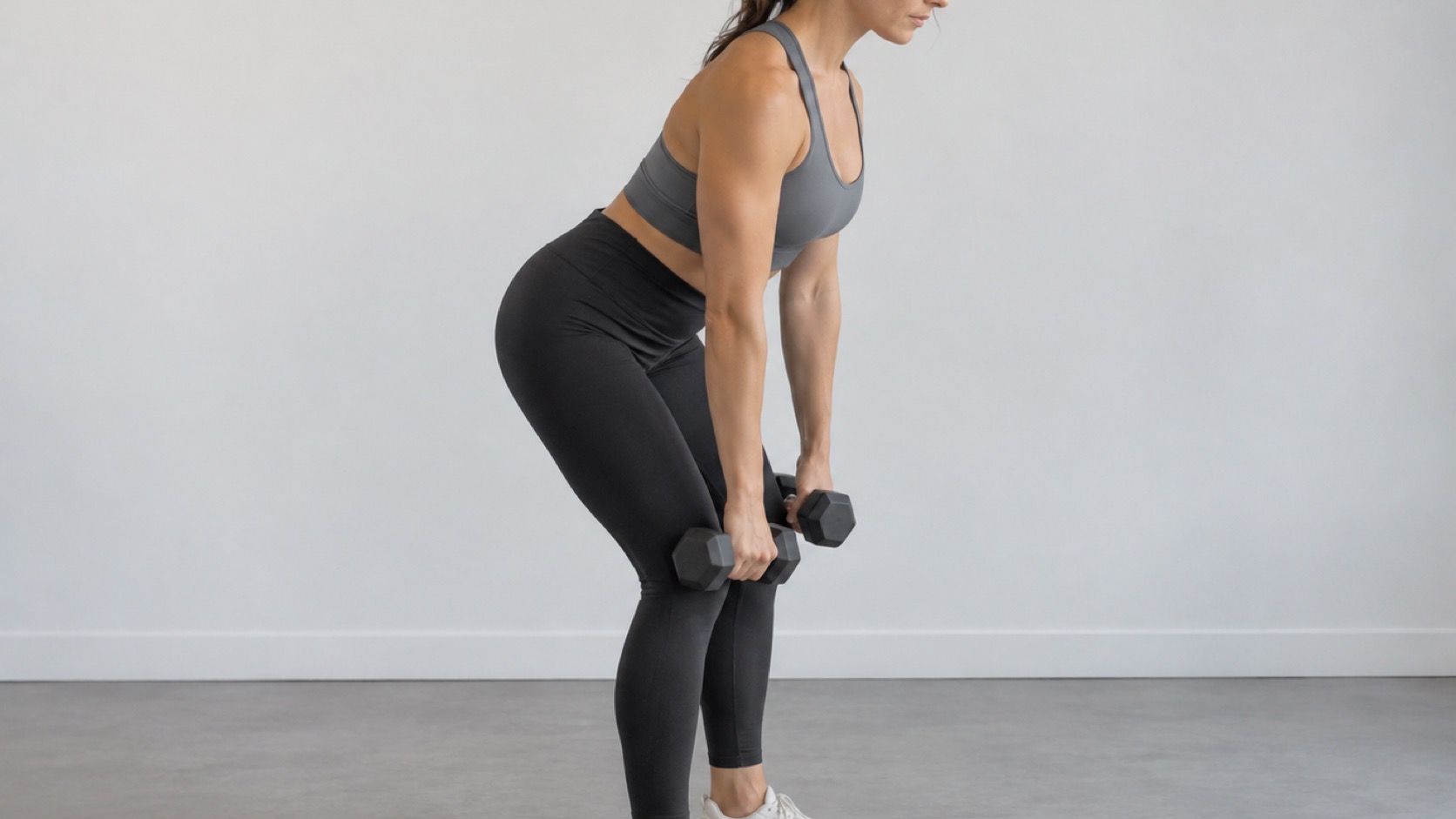 An adult performs a controlled light dumbbell hinge.
