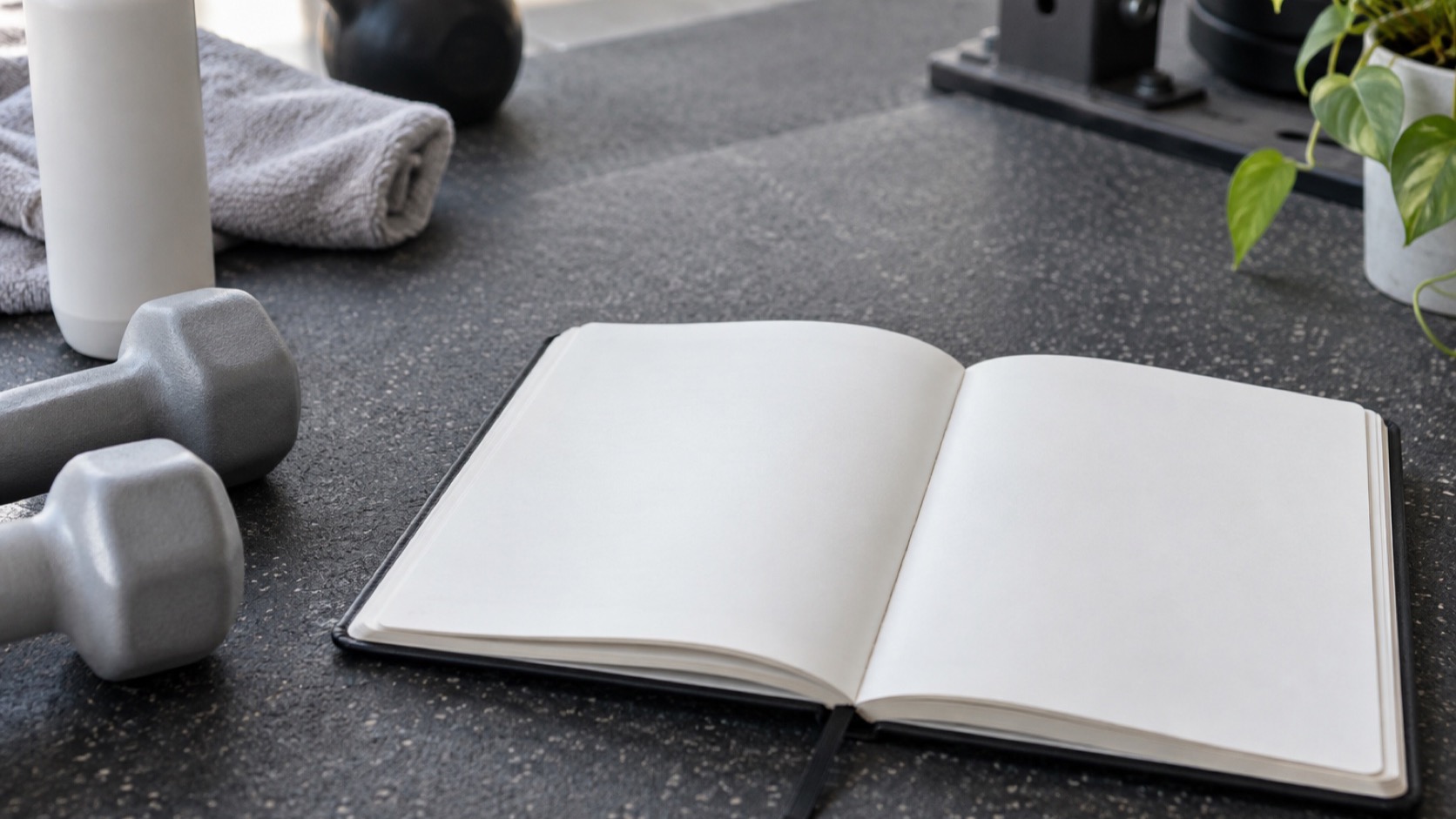 Adult writes in a training log beside light weights.