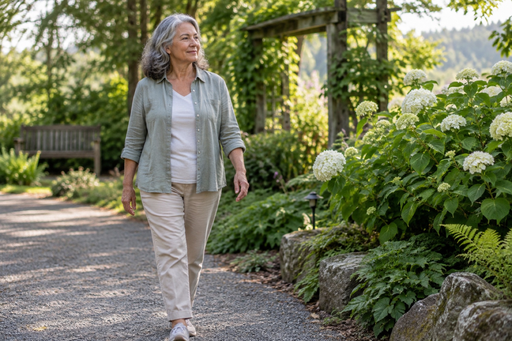 A woman walks slowly along a quiet garden path.